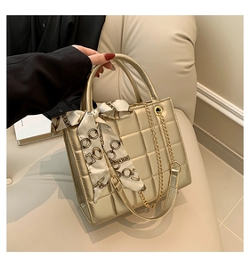 Details der goldenen Stepptasche mit Seidentuch am Griff und goldener Kette