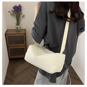 Close-up of off-white corduroy crossbody bag with soft texture and wide shoulder strap