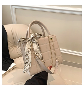 Detail der beige gesteppten Handtasche mit Seidentuchgriff und goldener Kette