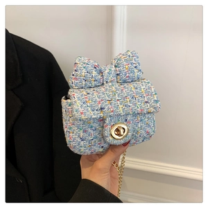 Detail of blue tweed crossbody bag featuring a large bow and gold metal swivel lock
