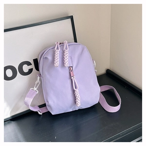 Detail view of lavender purple crossbody bag with unique woven zipper pulls and fabric texture