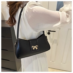 Détail d'un sac sous le bras noir avec boucle en métal dorée et texture en cuir mat