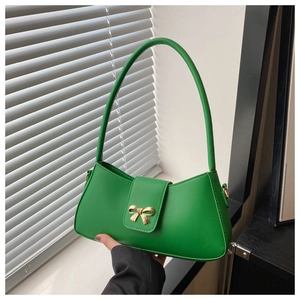 Detail of green leather baguette bag with golden bow hardware and long shoulder strap