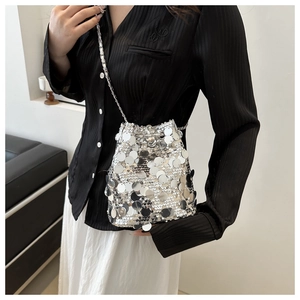 Detailed view of silver sequin bucket bag with shiny metallic disks and chain strap