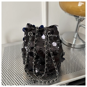 Detail showing shiny black sequins and metal chain strap of the drawstring bucket bag