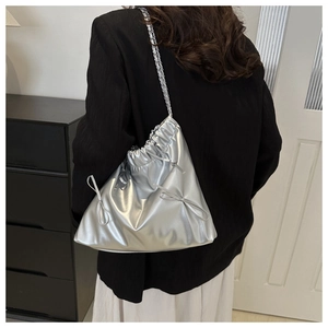 Sac seau argenté métallisé avec nœuds et bandoulière chaîne porté par un mannequin