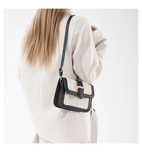 Détail de la texture en paille tressée et des finitions en cuir noir d'un sac bandoulière