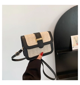 Détail du sac à bandoulière en paille tressée avec bordure en cuir noir et boucle dorée