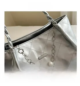 Detail of silver quilted tote bag featuring pearl and gold floral metal chain strap