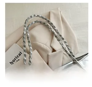 Detail of silver quilted handbag with braided handle and floral metal chain charm