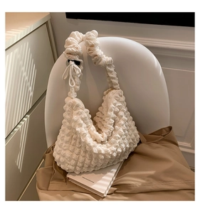 Detailed macro view of the white pleated fabric texture and ruffled strap of the shoulder bag