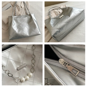 Detail of silver quilted tote bag featuring metal chains, pearls, and floral charms