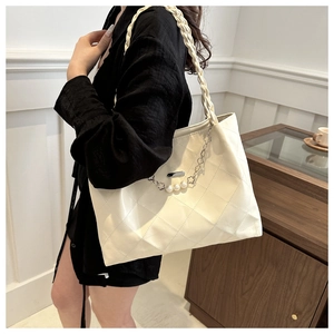 Detail of cream tote bag featuring quilted texture and decorative pearl floral metal chain