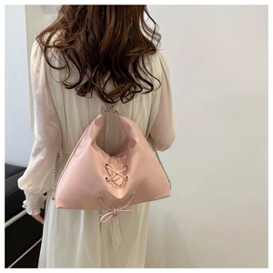 Detail of pink faux leather tote bag featuring lace-up design and bowknot accent