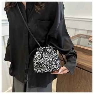 Detail view of a sequined drawstring bucket bag with silver and black metallic texture