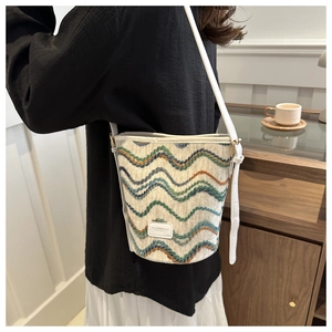 Detail of knit bucket bag with wave patterns, faux leather strap and Fashion label