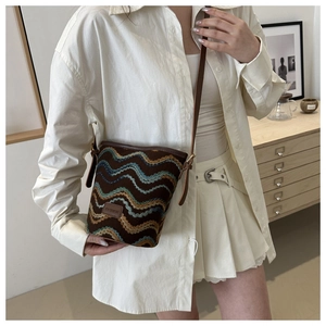 Detail of colorful wave pattern knit bucket bag with brown leather trim and fashion tag