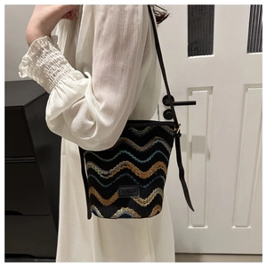 Model showing large capacity bucket bag with colorful wavy embroidery and leather strap