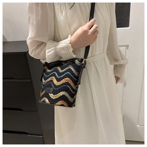 Detail of wave embroidery crossbody bag with fashion label on a white dress model