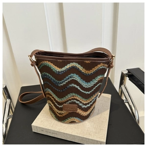 Macro view of wave-pattern knit fabric and dark brown leather trim on the bucket bag