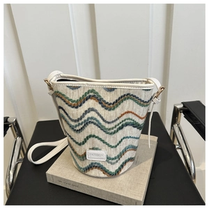 Detail of woven tweed bucket bag with colorful wavy patterns and leather fashion tag