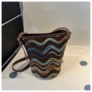 Detail of vintage knit bucket bag featuring retro wave patterns and brown leather strap