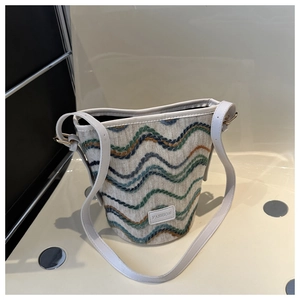 Macro detail of wave patterned woven fabric and white leather strap on the bucket bag