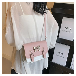 Detail of pink and silver crossbody bag with bow hardware and double strap buckle design