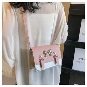 Detail of cross-body bag featuring a metallic bow and pink and silver contrast design