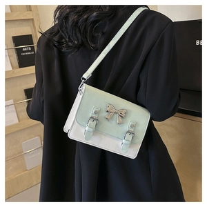 Detail view of mint green crossbody bag with silver bow hardware and buckled design
