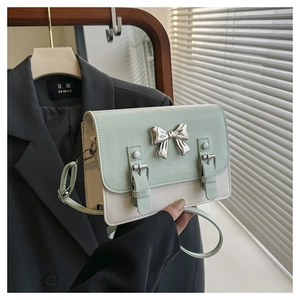 Close-up of mint green and white crossbody bag with silver bow and strap detail