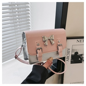 Close-up of pink and silver crossbody bag with a metal bow and dual buckle details