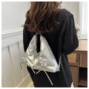 Détail du sac bandoulière argenté métallisé avec nœuds et bandoulière chaîne