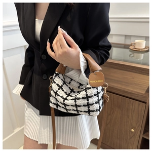 Détail du sac à main en tweed à carreaux avec poignée en cuir brun et étiquette mode