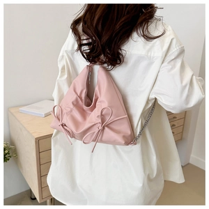 Détail du sac à bandoulière rose avec nœuds latéraux et bandoulière chaîne argent