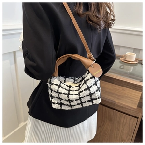 Détail du sac bandoulière en tweed à carreaux avec poignée en cuir marron et étiquette