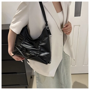 Détail du sac bandoulière plissé noir avec nœuds délicats et bandoulière en chaîne