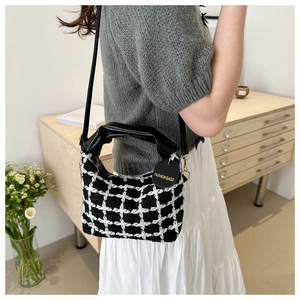 Détail du tissu à carreaux et de la poignée en cuir plissé d'un sac à bandoulière chic