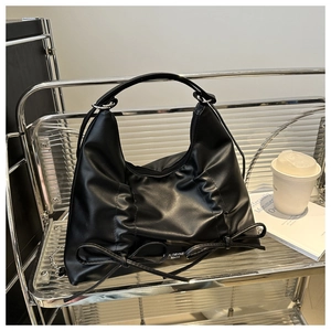 Détail du sac à bandoulière plissé noir avec nœuds décoratifs et chaîne argentée