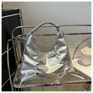 Détail d'un sac argenté métallisé avec nœuds sur un support d'exposition moderne