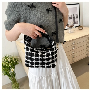 Détail du sac à main en tweed à carreaux avec poignée en cuir et ferrures dorées