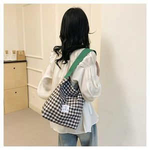 Détail du sac fourre-tout à carreaux avec bandoulière verte et étiquette tissée sur le devant