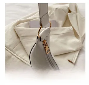 Close-up of golden zipper and hardware on white crescent moon shoulder bag