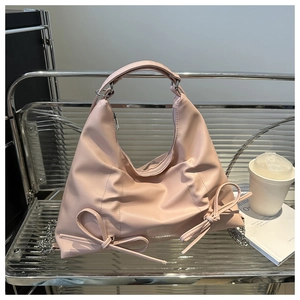 Détail du sac hobo rose avec nœuds sur étagère en verre avec décor style de vie