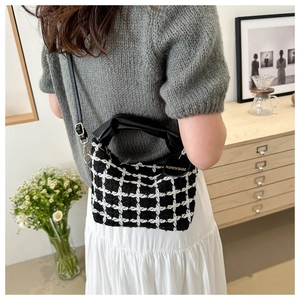 Gros plan du petit sac carré en tweed noir et blanc avec poignée en cuir plissée