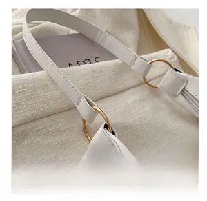 Detail of white leather shoulder bag showing golden metal ring strap attachment and stitching
