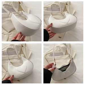 Macro view of white crescent bag featuring embossed heart detail and interior storage