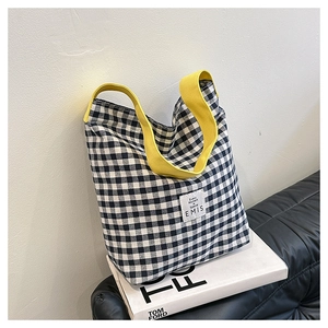 Détail d'un sac cabas à carreaux noir et blanc avec anses jaunes et étiquette logo EMIS