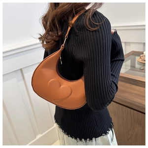 Detail of a brown half-moon underarm bag with embossed heart pattern on the front