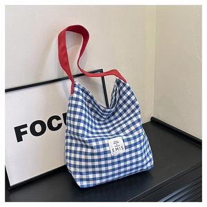 Détail du sac cabas en toile à carreaux bleu et blanc avec sangle rouge et étiquette EMIS